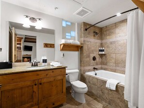 A modern bathroom with a wooden vanity, a toilet, a bathtub, and a shower area with tiled walls. - Newpark 306 | Private Hot Tub | Kitchenette | Olympic Park & Mtn View | Fireplace | Pool & Hot Tub (Park City)