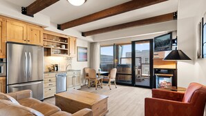 A modern kitchen with a stainless steel refrigerator, wooden cabinets, and a dining area with a table and chairs. - Newpark 314 | Private Hot Tub | Kitchenette | Mtn & Preserve View | Fireplace | Pool & Hot Tub (Park City)