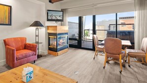 A cozy living room with a fireplace, comfortable seating, and a large window offering a view of the outside. - Newpark 315 | Private Hot Tub | Kitchenette | Mountain & Preserve Views | Fireplace | Washer/Dryer (Park City)