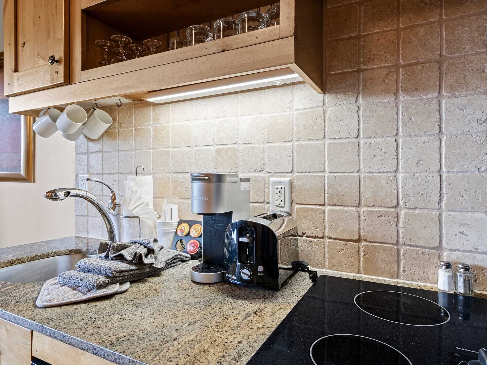 A kitchen with a granite countertop, a coffee maker, a toaster, and a sink.