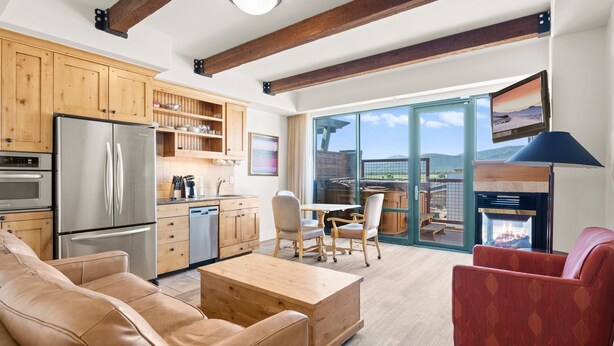 A spacious living area with a kitchen, a fireplace, and a balcony with a scenic view. - Newpark 416 | Private Hot Tub | Kitchenette | Mountain & Preserve Views | Fireplace | Top Floor (Park City)