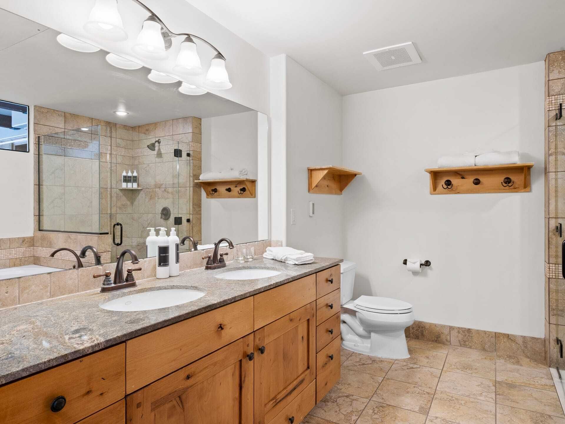 A modern bathroom with a double sink vanity, a large mirror, and a shower enclosure.