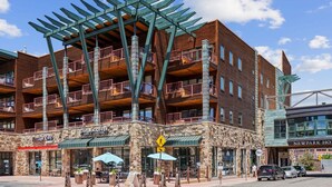 A multi-story building with a stone facade, balconies, and a coffee shop named "CUPPA COFFEE" at the ground level. - Newpark 416 | Private Hot Tub | Kitchenette | Mountain & Preserve Views | Fireplace | Top Floor (Park City)