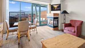 A spacious living room with a large sliding glass door leading to an outdoor area, a fireplace, and a cozy seating arrangement. - Newpark 416 | Private Hot Tub | Kitchenette | Mountain & Preserve Views | Fireplace | Top Floor (Park City)