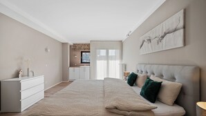 A bedroom with a large bed, a dresser, a painting on the wall, and a view of the kitchen in the background. - Black Forest moment at Monbachtal (Bad Liebenzell)