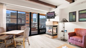 Una sala de estar moderna con chimenea, una mesa de comedor con sillas, un sofá y un televisor montado en la pared.