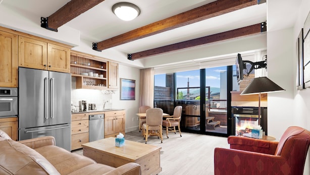 Una cocina moderna con vigas de madera, un refrigerador de acero inoxidable y un comedor con vistas.