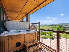 Ein Whirlpool auf einer Holzterrasse mit Blick auf eine grüne Landschaft und Hügel.
