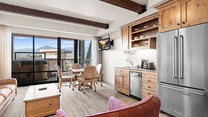 Eine moderne Küche mit Holzschränken, einem Edelstahlkühlschrank und einem Essbereich mit Tisch und Stühlen.