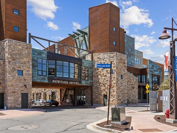 A modern hotel with a stone facade, a glass entrance, and a clear blue sky.