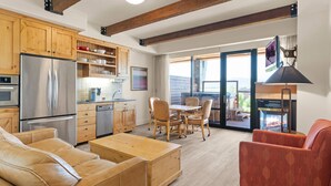 Una cocina moderna con armarios de madera, un refrigerador de acero inoxidable y una zona de comedor con mesa y sillas de madera.