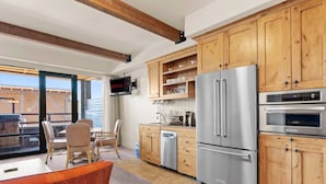 Una cocina moderna con armarios de madera, electrodomésticos de acero inoxidable y una televisión integrada.