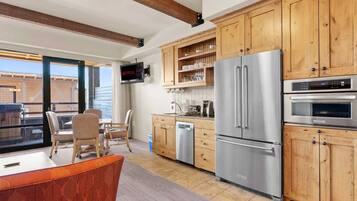 A modern kitchen with wooden cabinets, stainless steel appliances, and a built-in TV.