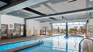 An indoor swimming pool with clear water, a tiled floor, and a ceiling with recessed lighting.