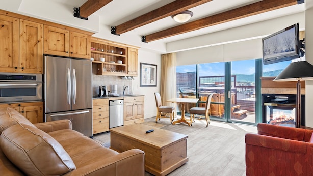 A modern kitchen with wooden cabinets, stainless steel appliances, and a dining area with a view.