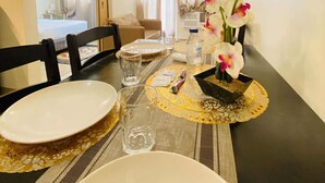A dining area with a table set for two, a vase of flowers, and a view into the living room. - Room-cozy Iloilo City Condo Room With Sh (Iloilo)