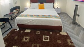 Ein Hotelzimmer mit Bett, Fernseher, Schreibtisch und Stuhl.