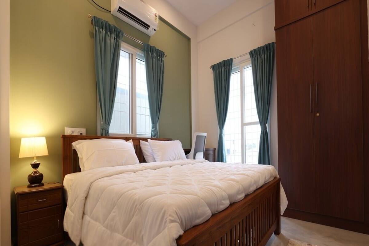 A bedroom with a wooden bed, green walls, and a large wardrobe.