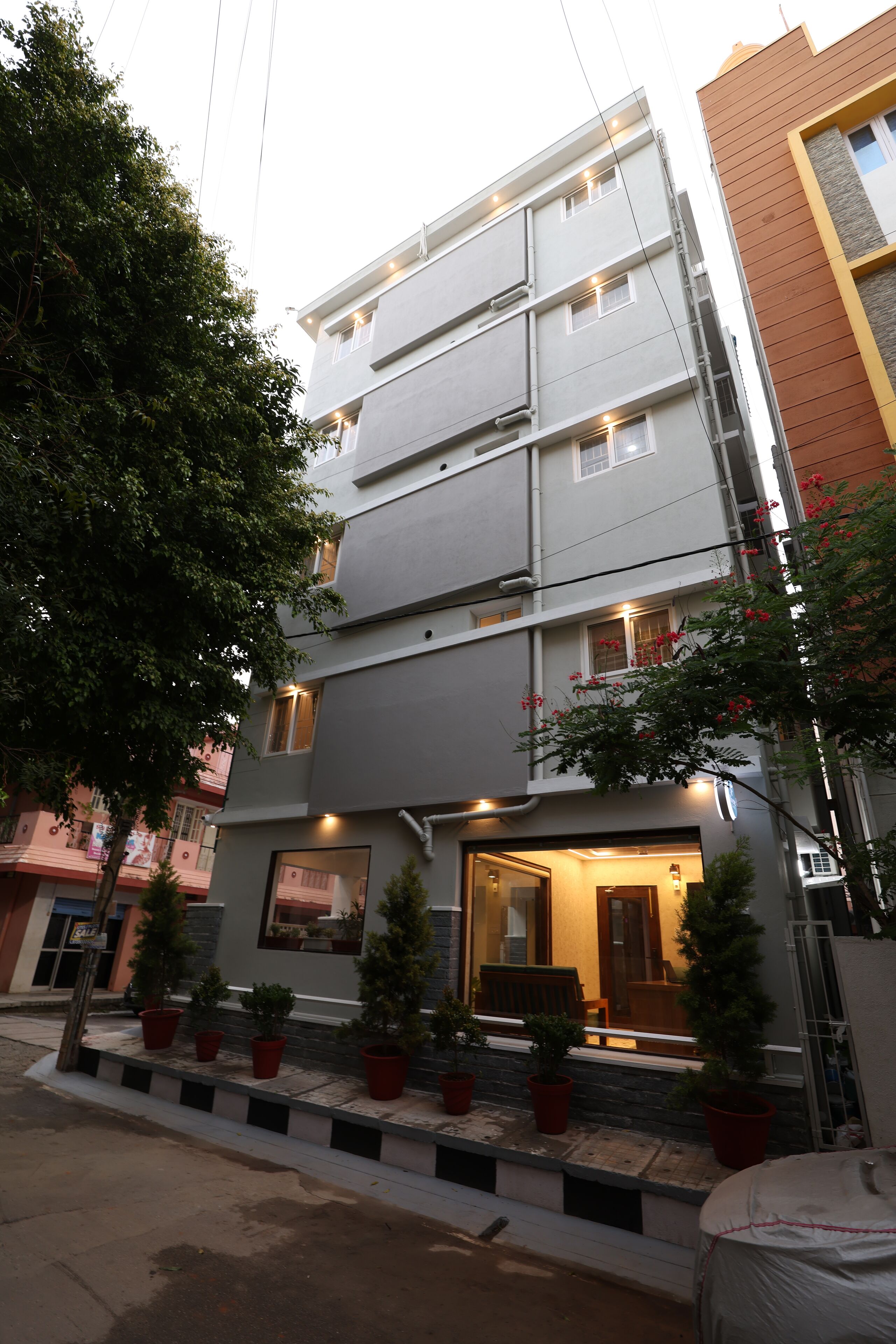 Een meerlaags gebouw met een modern ontwerp, met een balkon met potplanten en een goed verlichte entree.