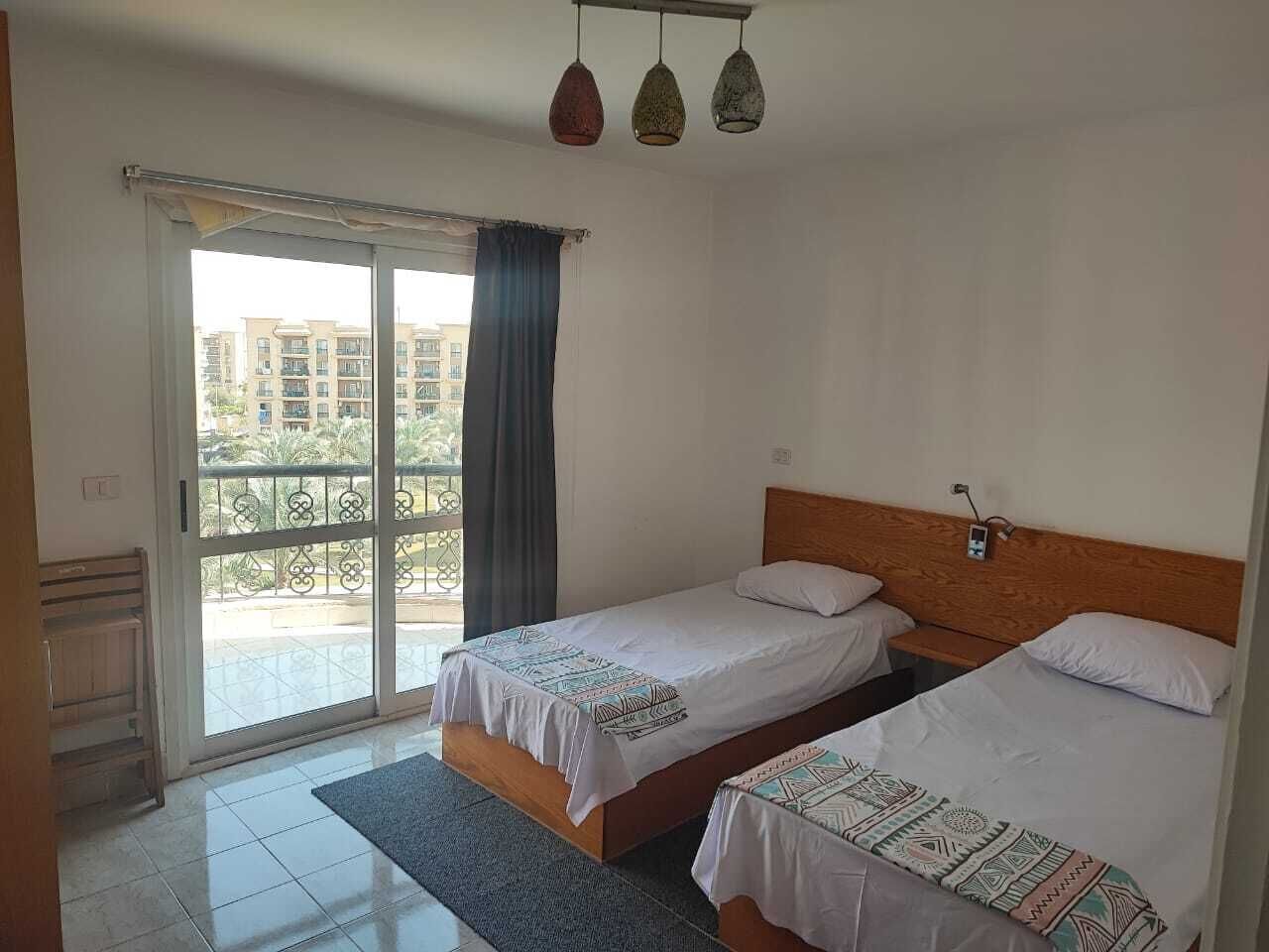 Habitación de hotel con dos camas, un balcón y vistas a edificios.