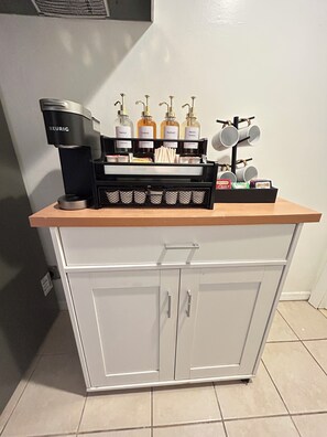 A coffee station with a Keurig coffee maker, various coffee pods, and a mug rack. - AUREA Stays /Private 2BR Suite / Free Parking /Near EWR (Newark)