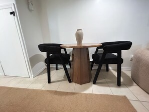 Ein kleiner Essbereich mit einem runden Holztisch und zwei schwarzen Stühlen.