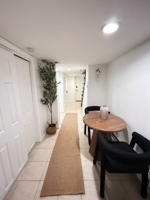 A hallway with a dining table and chairs, a plant, and a rug. - AUREA Stays /Private 2BR Suite / Free Parking /Near EWR (Newark)