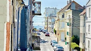 Una calle estrecha flanqueada por edificios, con cielo despejado y coches estacionados.