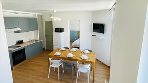 Una cocina moderna con comedor, un televisor en la pared y una mesita con un jarrón.