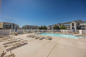 Et hotelområde med swimmingpool, liggestole og flere etagebygninger.
