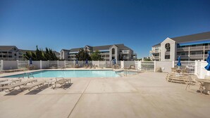 A hotel with a swimming pool, lounge chairs, and a covered seating area.