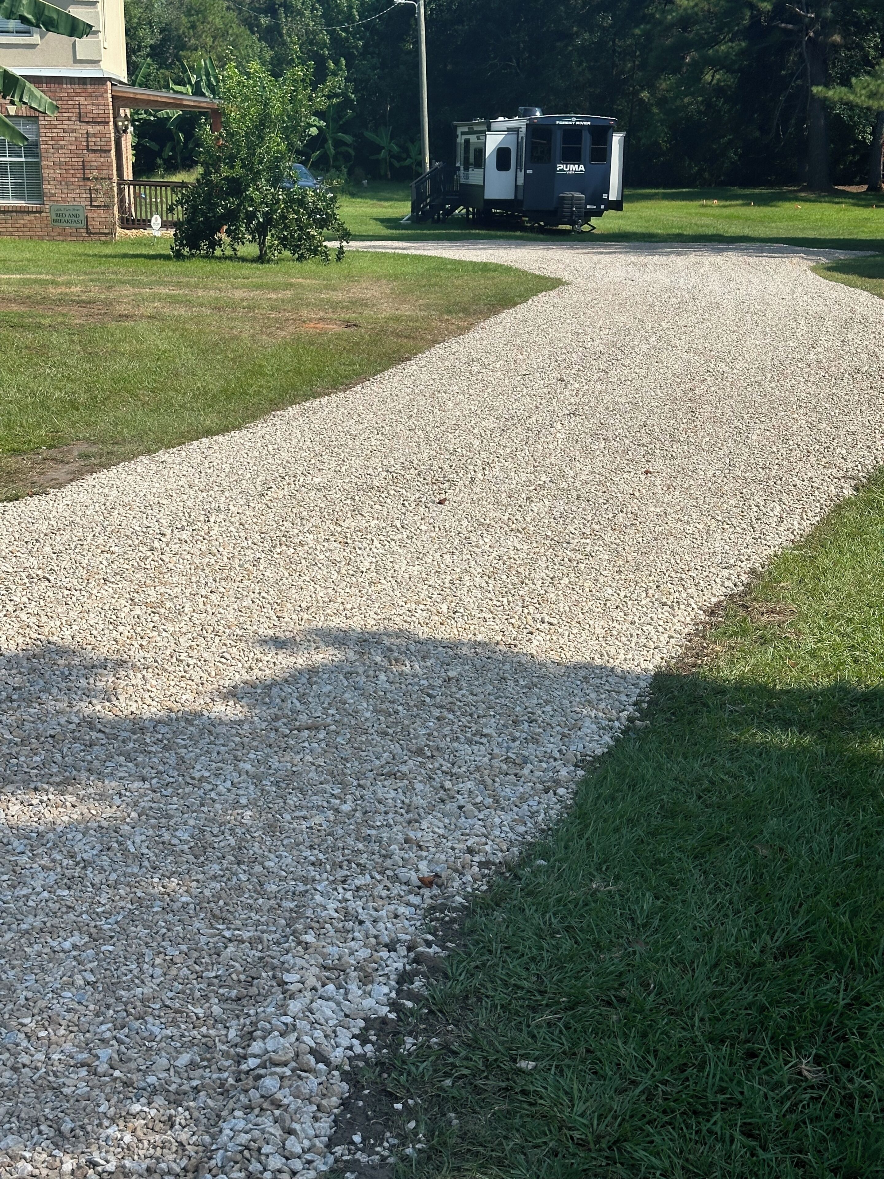 Een grindpad dat leidt naar een gebouw met een bordje dat een bed en ontbijt aangeeft.