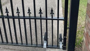 Un camino de entrada con puerta metálica que lleva a un edificio de fachada de ladrillo.
