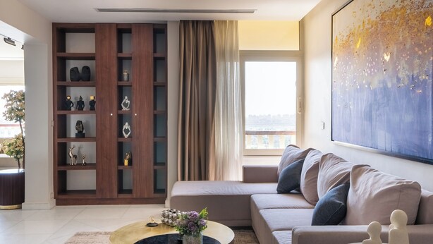 A modern living room with a beige sofa, a round coffee table, and a wooden bookshelf. - Easy Rental/ Serviced Apartment In Corniche El Maadi (Corniche El Maadi Cairo Governorate)