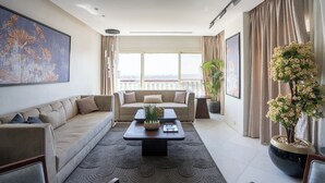 A modern living room with a sofa, a coffee table, and a large window with a view. - Easy Rental/ Serviced Apartment In Corniche El Maadi (Corniche El Maadi Cairo Governorate)