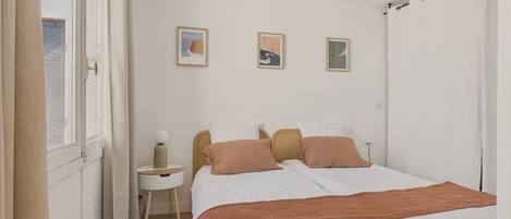 Quarto com cama, mesa lateral e luminária pendente.