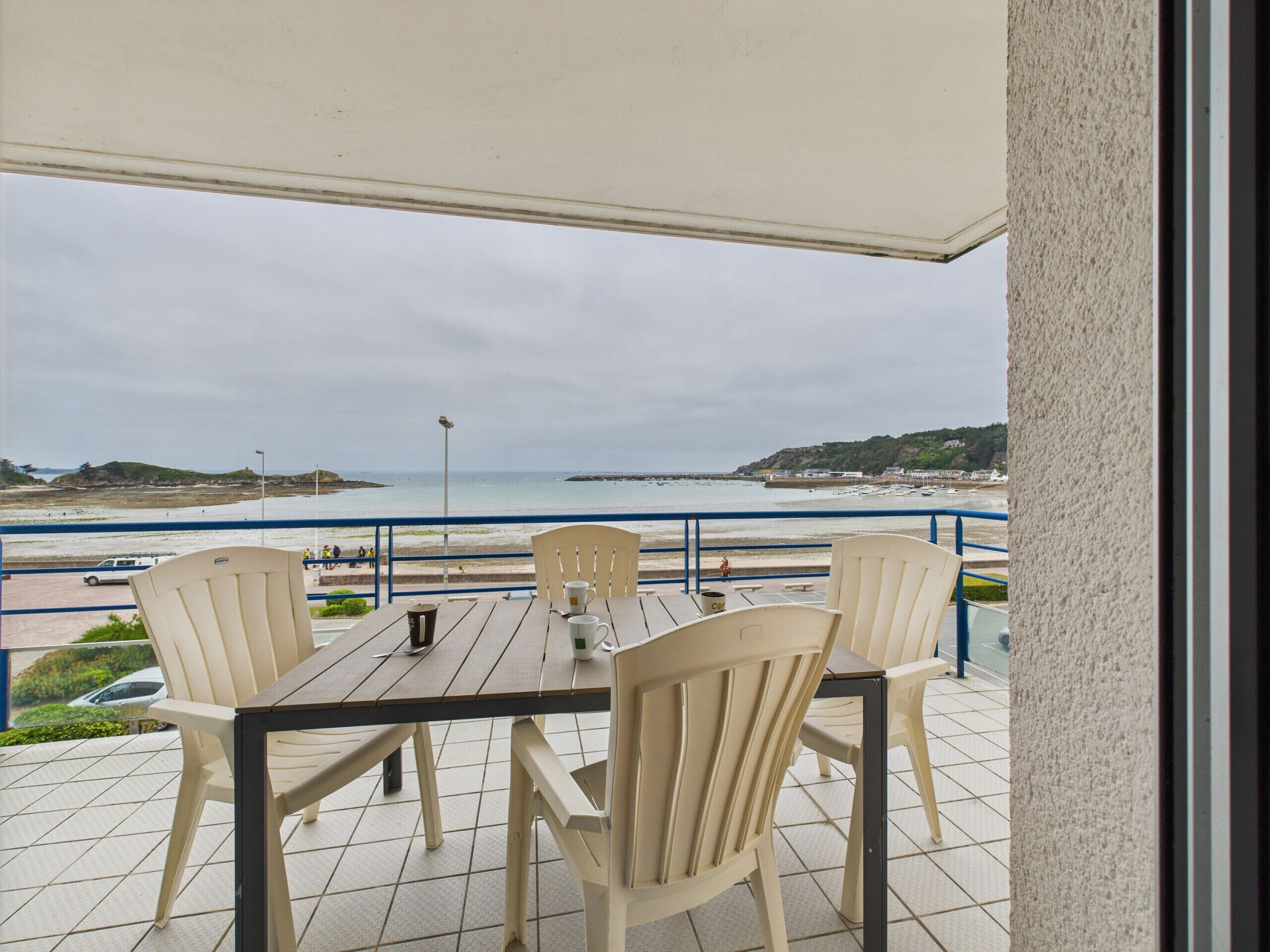 A patio with a table and chairs overlooking a beach.