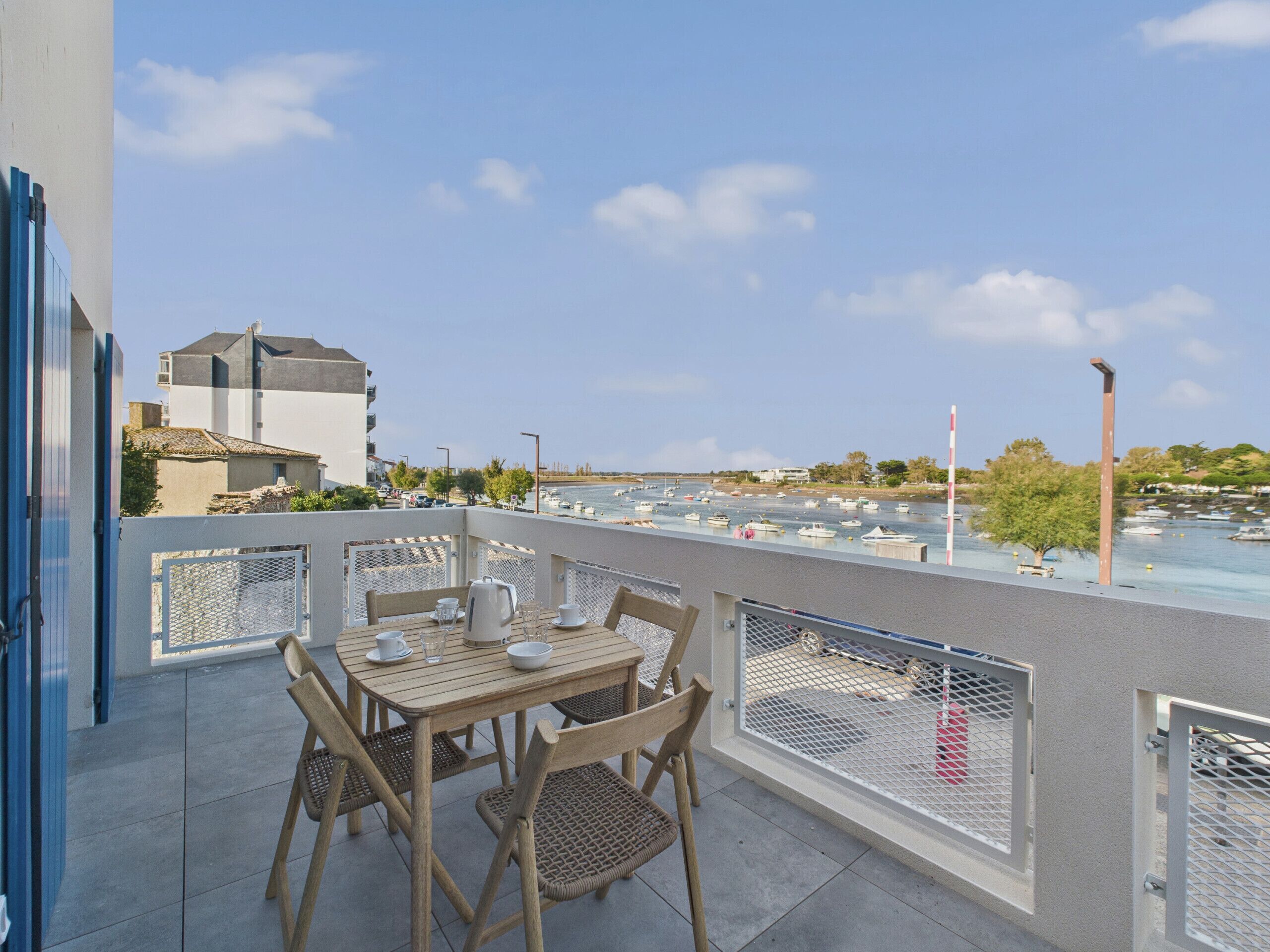 A balcony with a table set for two, overlooking a marina with boats.