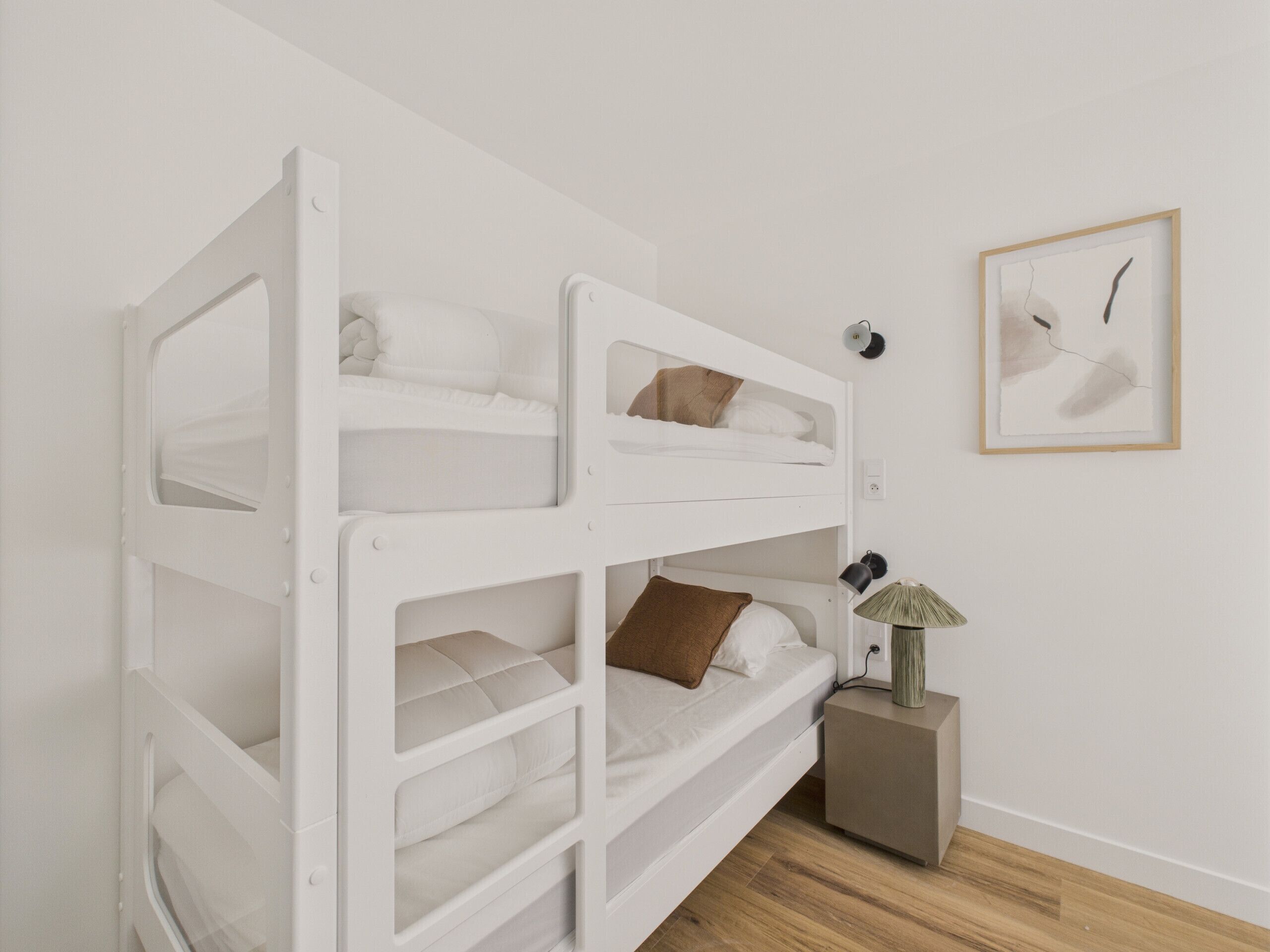 Une chambre avec un lit superposé, une table de chevet et une lampe.