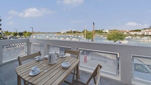Una terraza con mesa lista para comer, con vistas a un puerto deportivo y barcos.