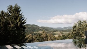 A modern infinity pool with a clear view of a mountainous landscape.