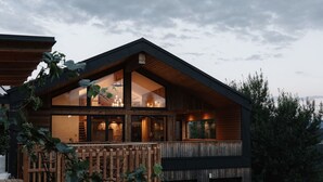 A modern house with a wooden deck, large windows, and a stone wall interior.