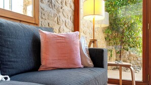 A cozy room with a grey sofa, a pink pillow, and a wooden table with a lamp. - Charming barn in the Matarraña, patio with barbecue and AC - Casa de las Letras (Liedo)