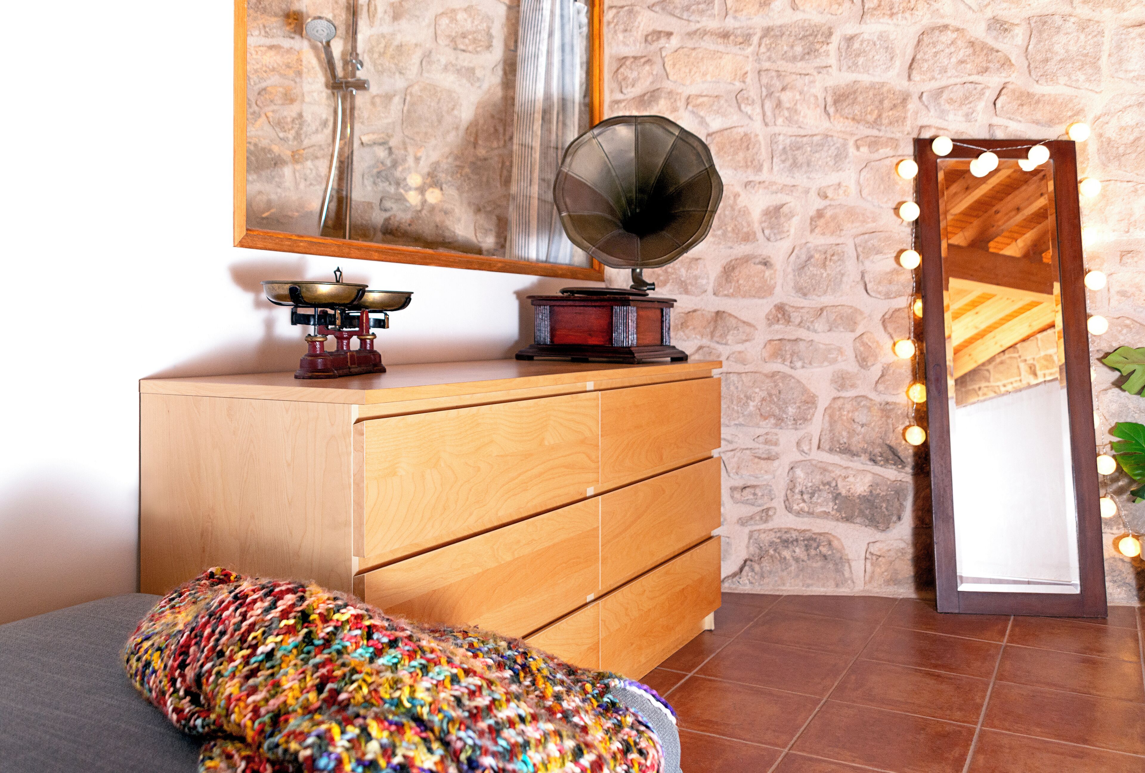 Una habitación con un aparador de madera, un tocadiscos y un espejo con iluminación.