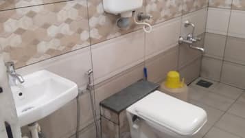 A bathroom with a white sink, toilet, and a small trash bin.