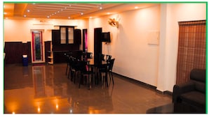A spacious room with a polished floor, a reception desk, a seating area with chairs, and a sofa. - Green Mount Residency (Devikolam)