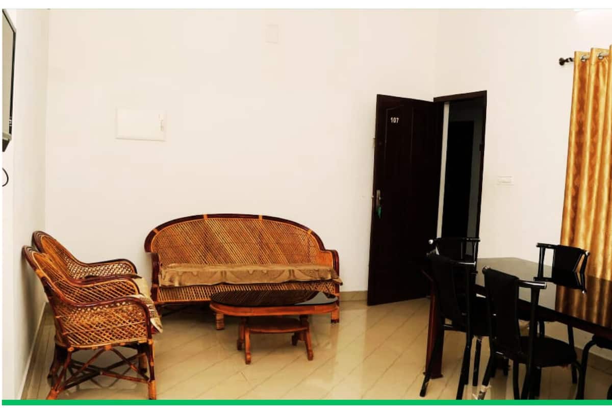 A room with a sofa, two armchairs, a small table, and a dining table with chairs.