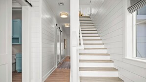 A staircase with white walls and wooden steps leading to a landing.