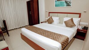 Une chambre d’hôtel avec un grand lit, une table de chevet en bois, une chaise et une vue sur une étendue d’eau par la fenêtre.