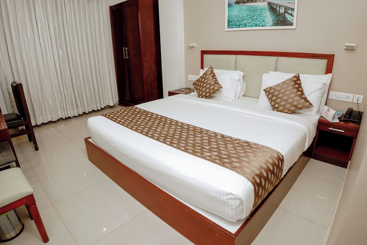 A hotel room with a large bed, a wooden nightstand, a chair, and a view of a body of water through the window.